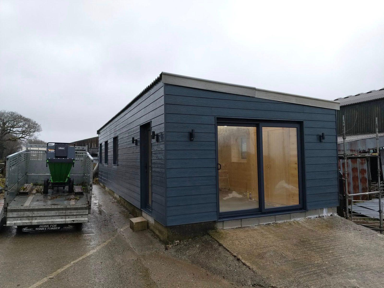 Completed navy timber-clad garden room with sliding glazed doors