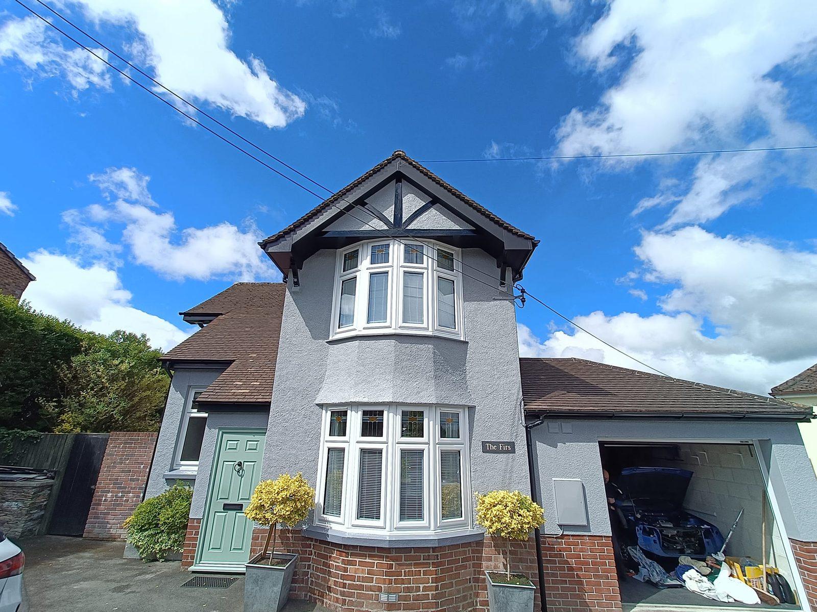 Detached rendered house with bay windows and a sage front door