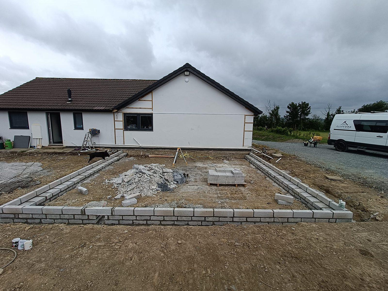 New extension footings and groundworks beside a finished bungalow