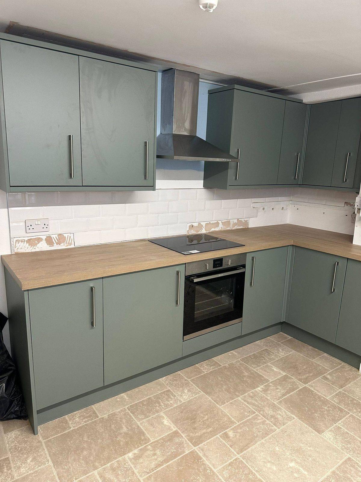 Sage-green shaker kitchen with oak worktops and induction hob
