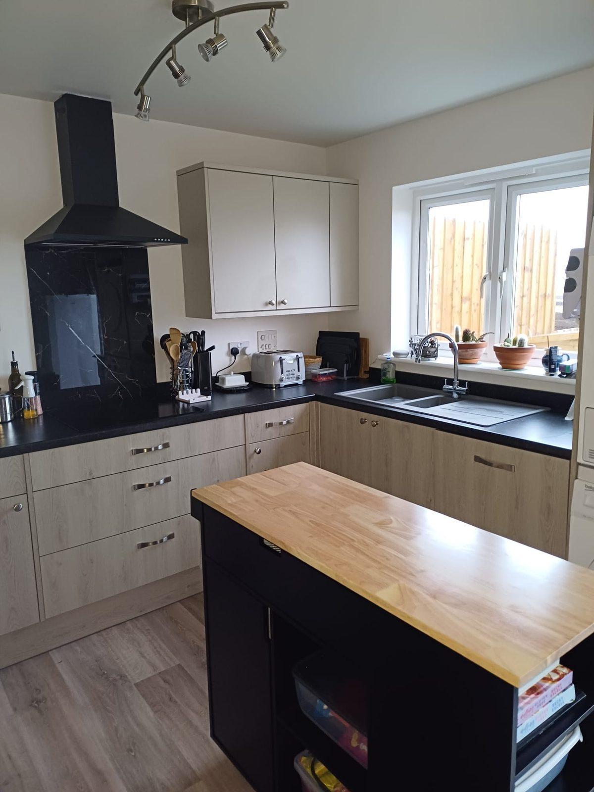 Modern kitchen with oak-effect units, black worktop and marble splashback