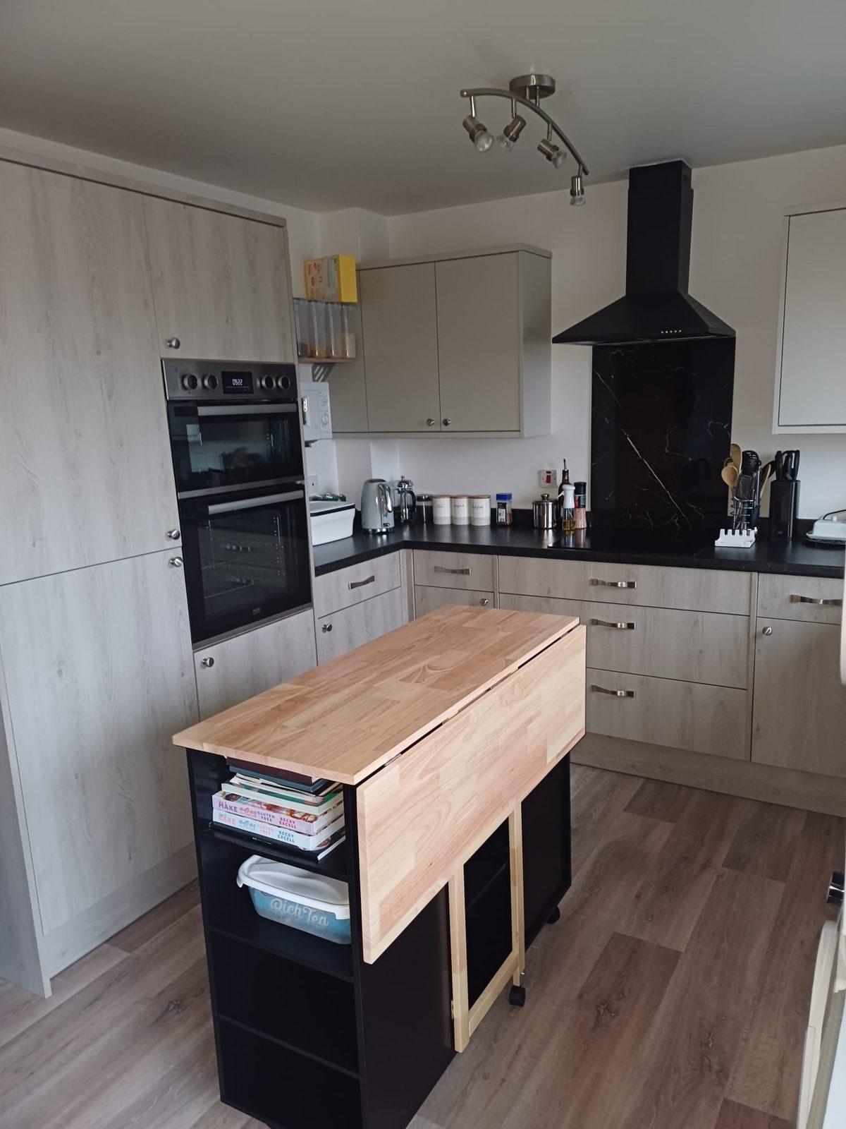 Kitchen with grey units, double oven and a timber island