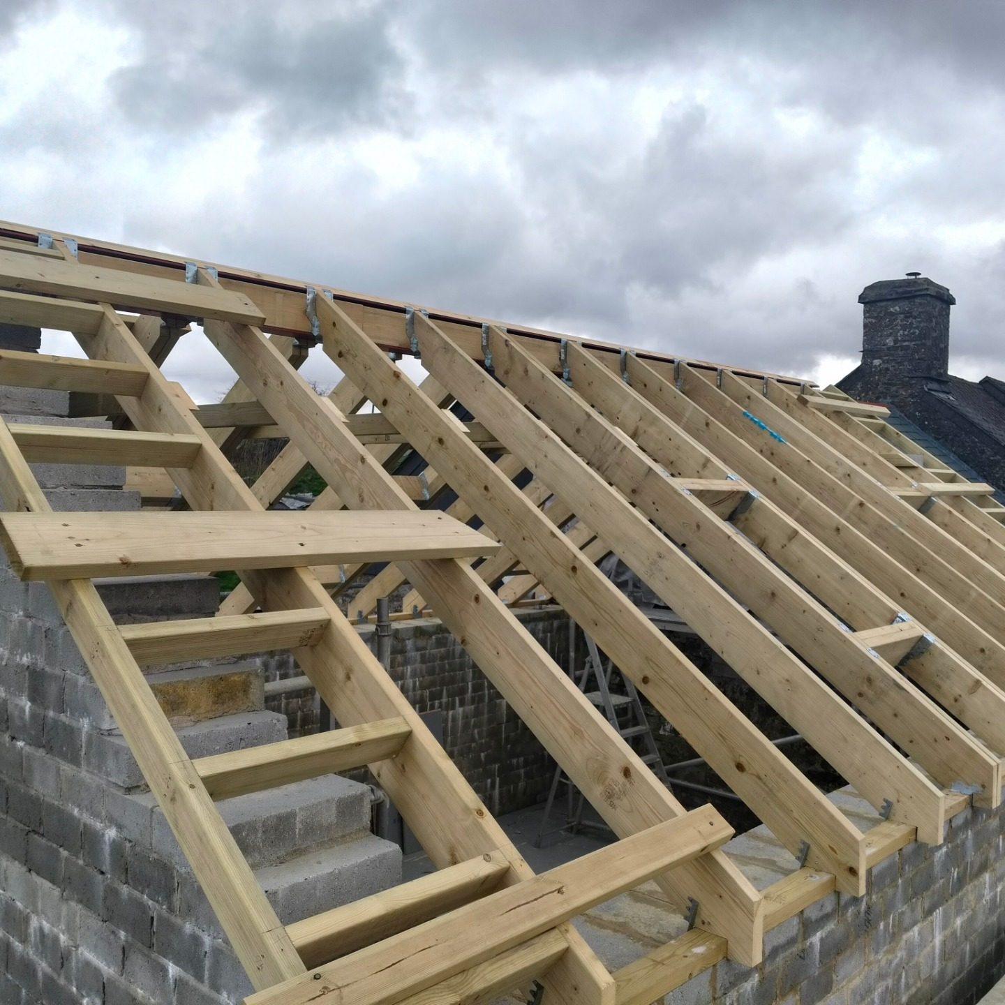 New pitched timber roof structure with chimney beyond